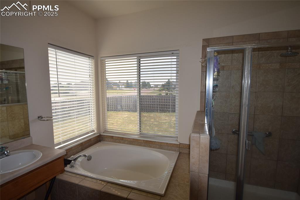 Image 30 of 50: Full bathroom with a bath, a stall shower, and vanity