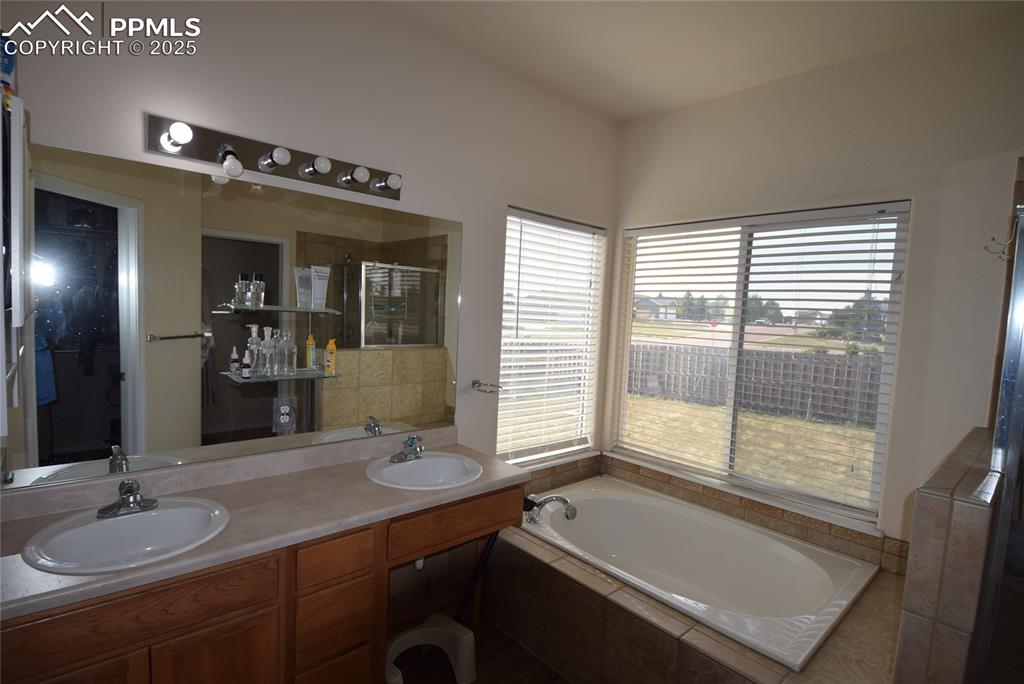 Image 32 of 50: Bathroom with a garden tub, a stall shower, and double vanity