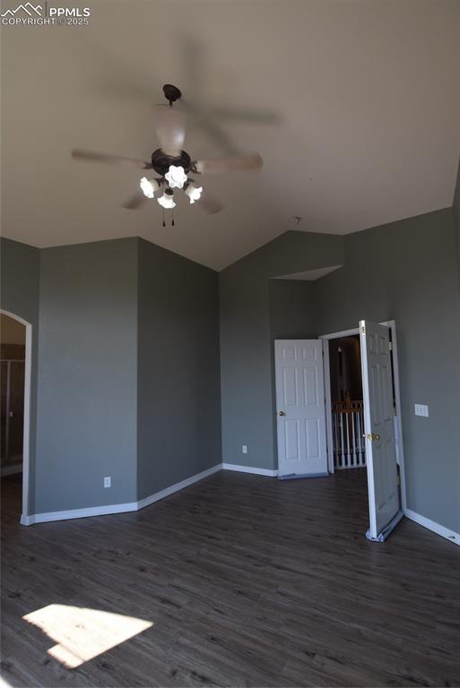 Image 34 of 50: Spare room featuring dark wood-style floors, lofted ceiling, arched walkway