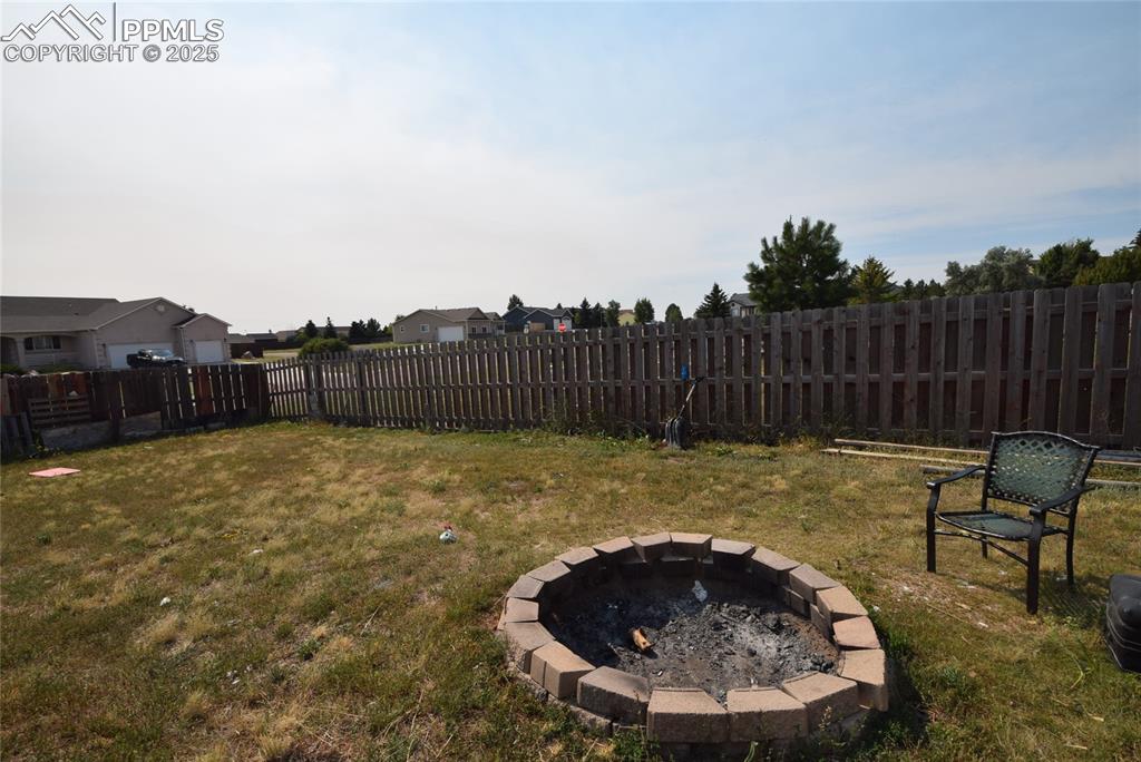 Image 42 of 50: Fenced backyard featuring a fire pit and a residential view