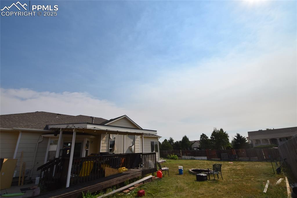 Image 47 of 50: Fenced backyard featuring a fire pit and a deck