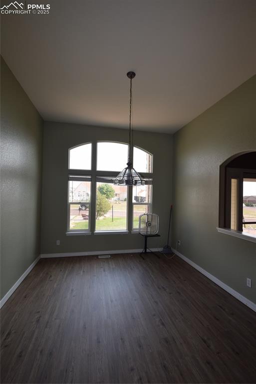 Image 9 of 50: Unfurnished dining area featuring dark wood finished floors and baseboards