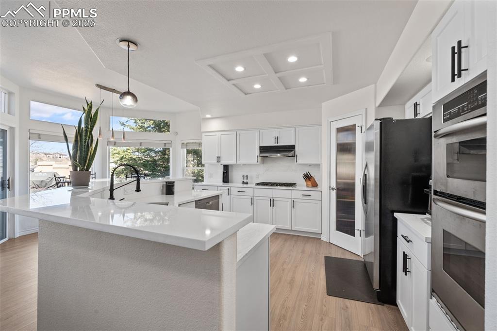 Image 12 of 49: Kitchen featuring white cabinets, a large island with sink, stainless steel