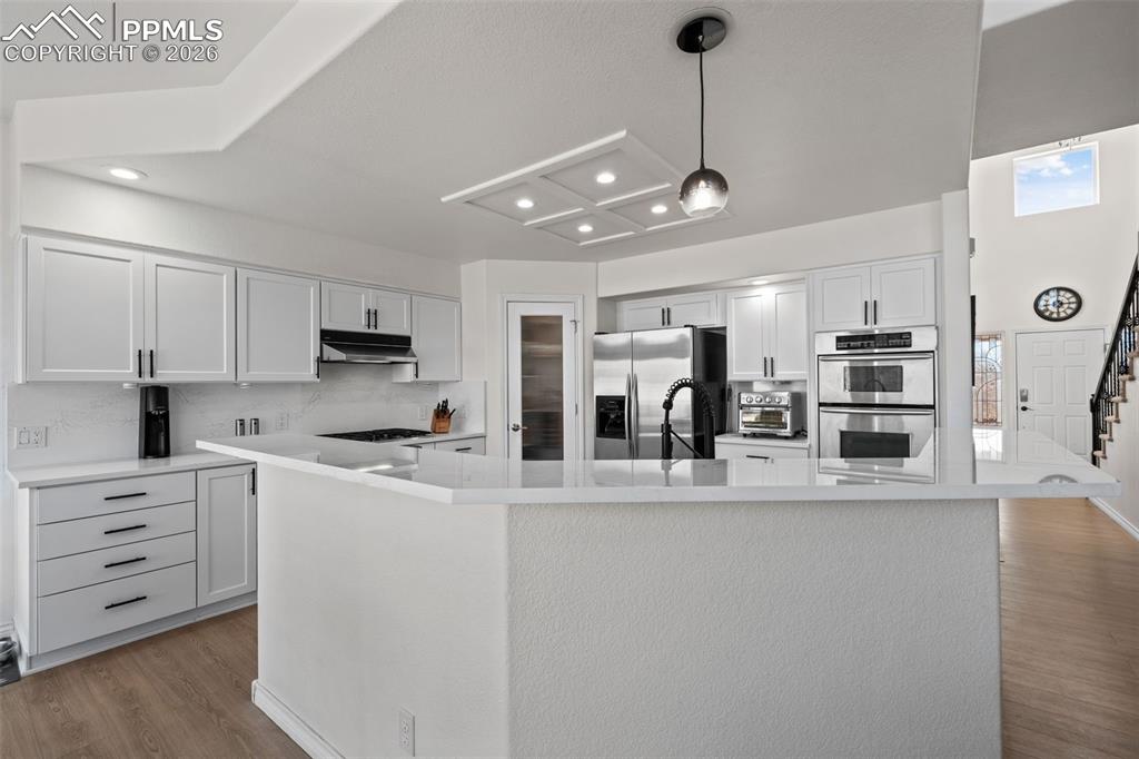 Image 13 of 49: Kitchen featuring light wood-type flooring, a spacious island, stainless st