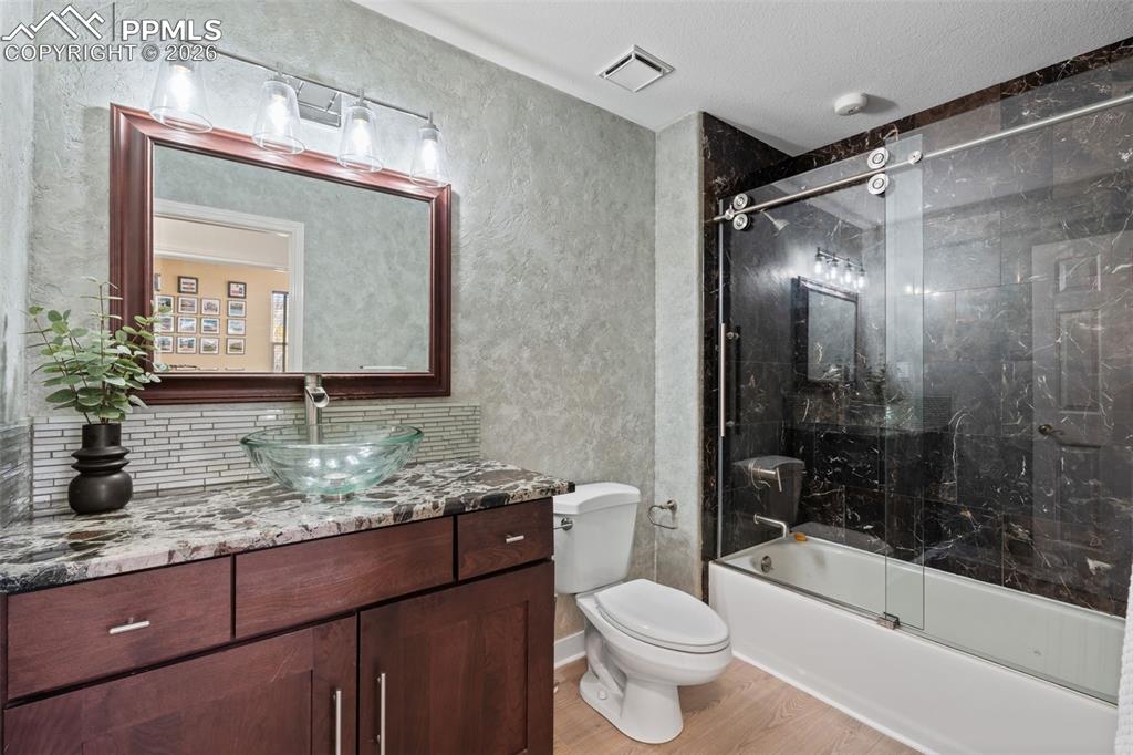 Image 19 of 49: Bathroom with vanity, a textured wall, light wood finished floors, and comb