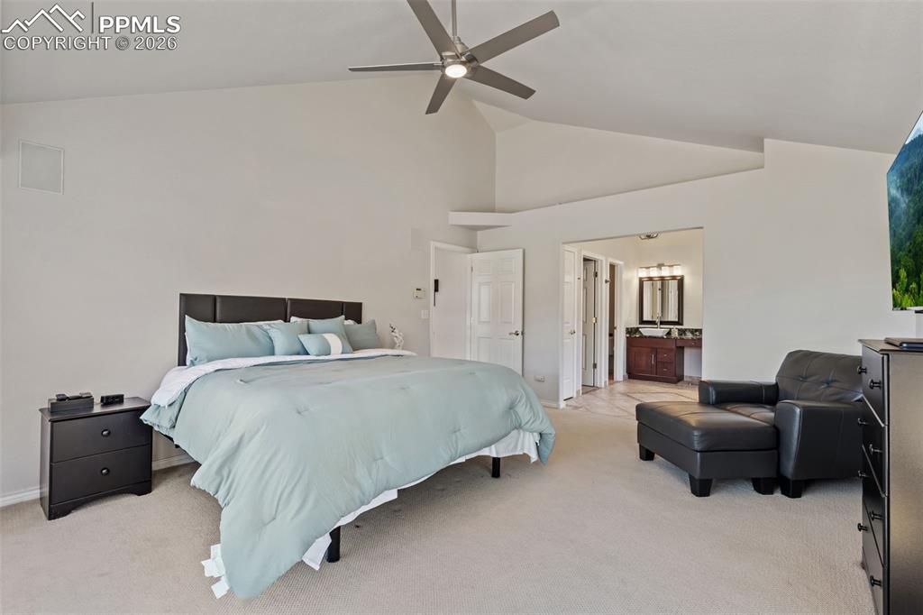 Image 24 of 49: Bedroom featuring light carpet, vaulted ceiling, a ceiling fan, and ensuite