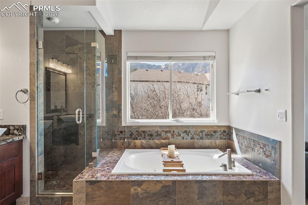 Image 28 of 49: Bathroom featuring a stall shower, a bath, and vanity