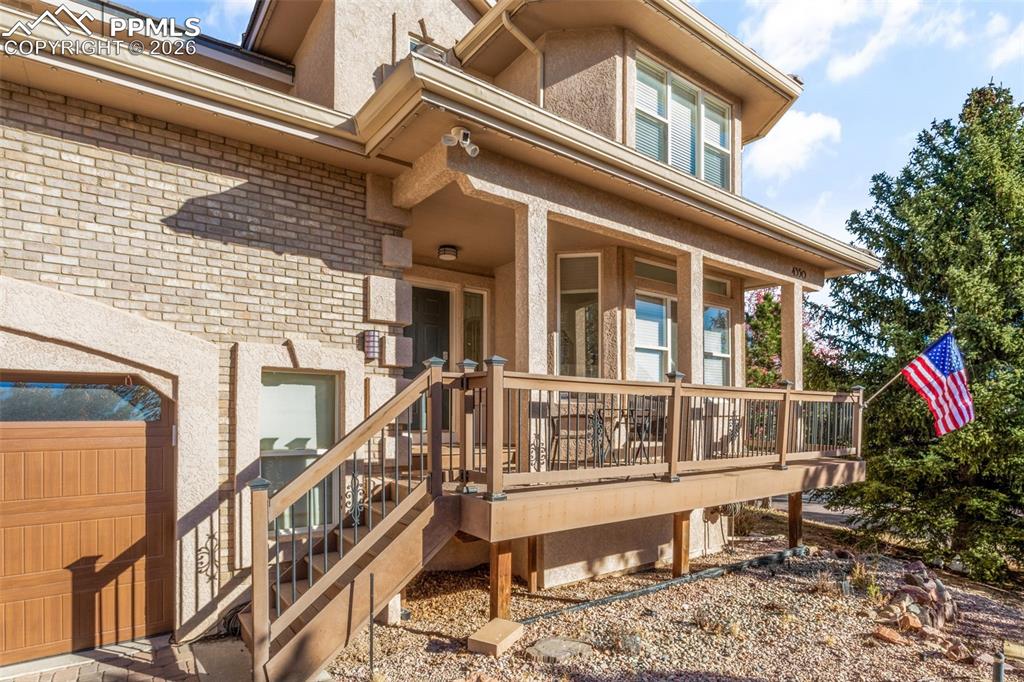 Image 3 of 49: View of exterior entry with brick siding, a deck, and stucco siding