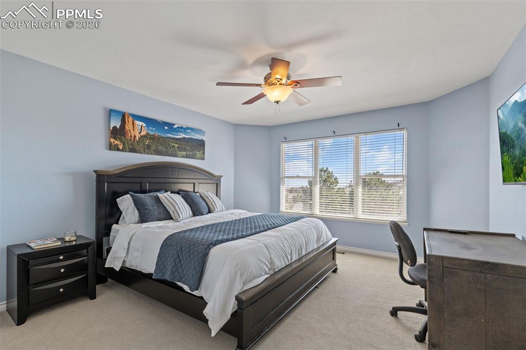 Image 30 of 49: Carpeted bedroom with a desk and a ceiling fan