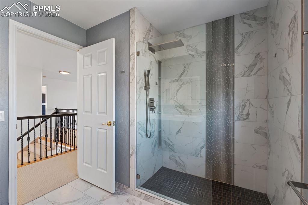 Image 32 of 49: Bathroom with a marble finish shower and light marble finish flooring