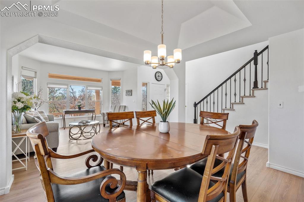 Image 7 of 49: Dining room with light wood-type flooring, a tray ceiling, and a chandelier