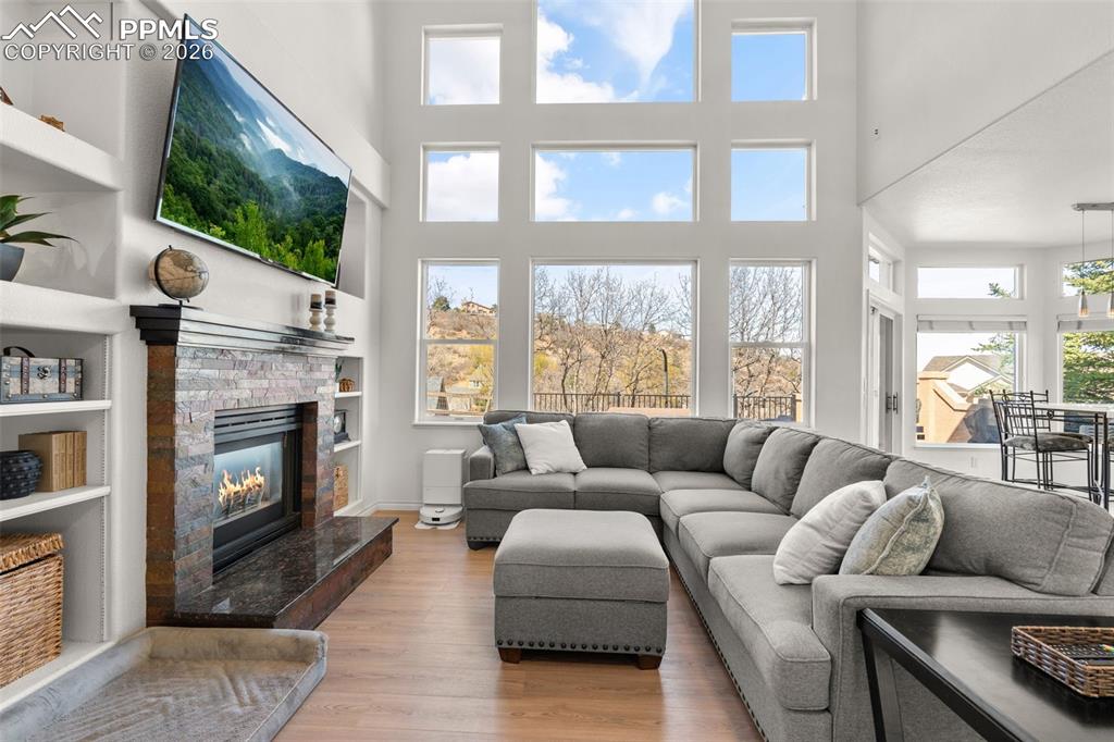Image 9 of 49: Living area featuring a glass covered fireplace, wood finished floors, a hi