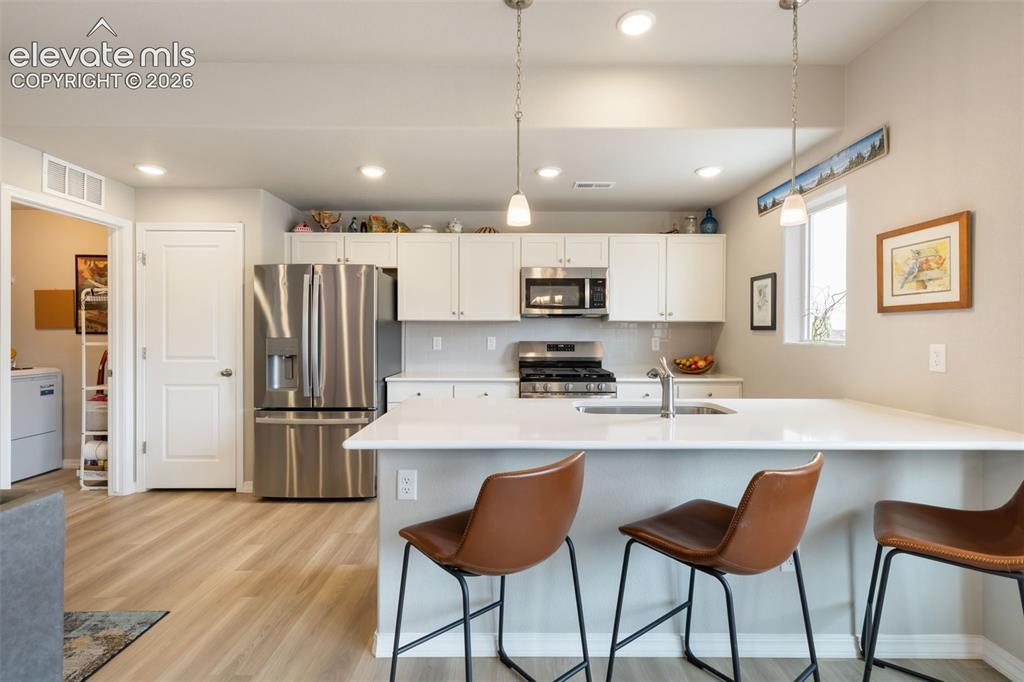 Image 10 of 28: Modern kitchen featuring a large island with integrated sink, stainless ste