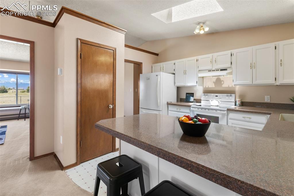 Image 21 of 50: Kitchen features granite transformation countertop and skylight