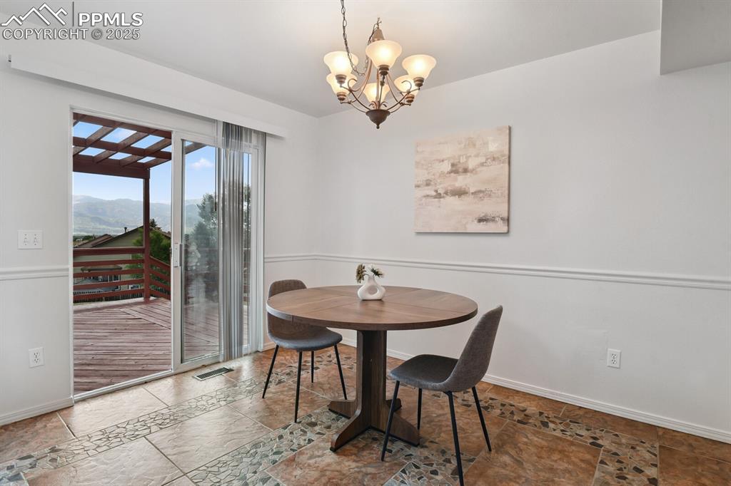 Image 10 of 45: Dining area featuring a chandelier, a mountain view, and stone tile floors