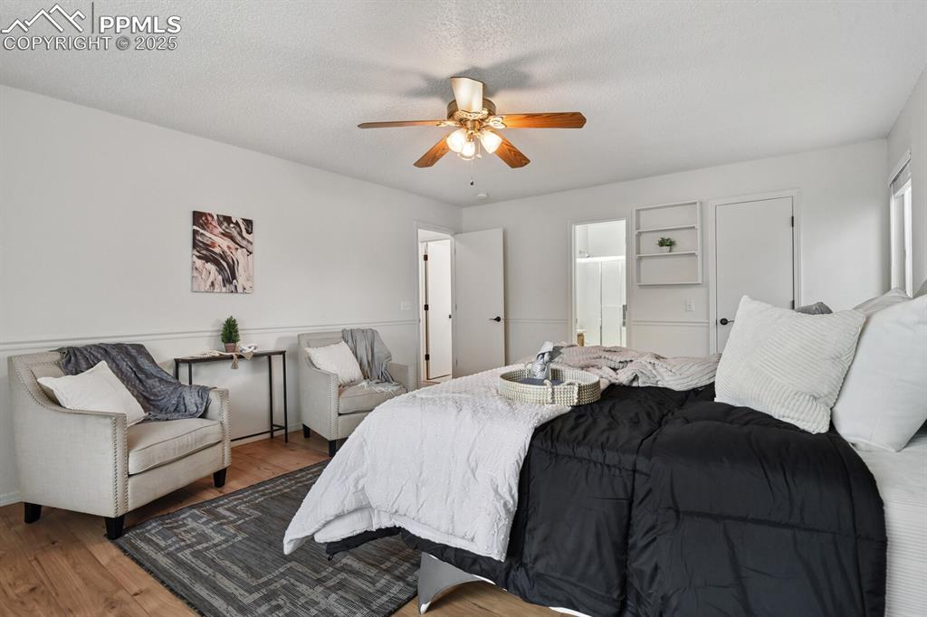Image 19 of 45: Bedroom with wood finished floors, ceiling fan, a textured ceiling, and con