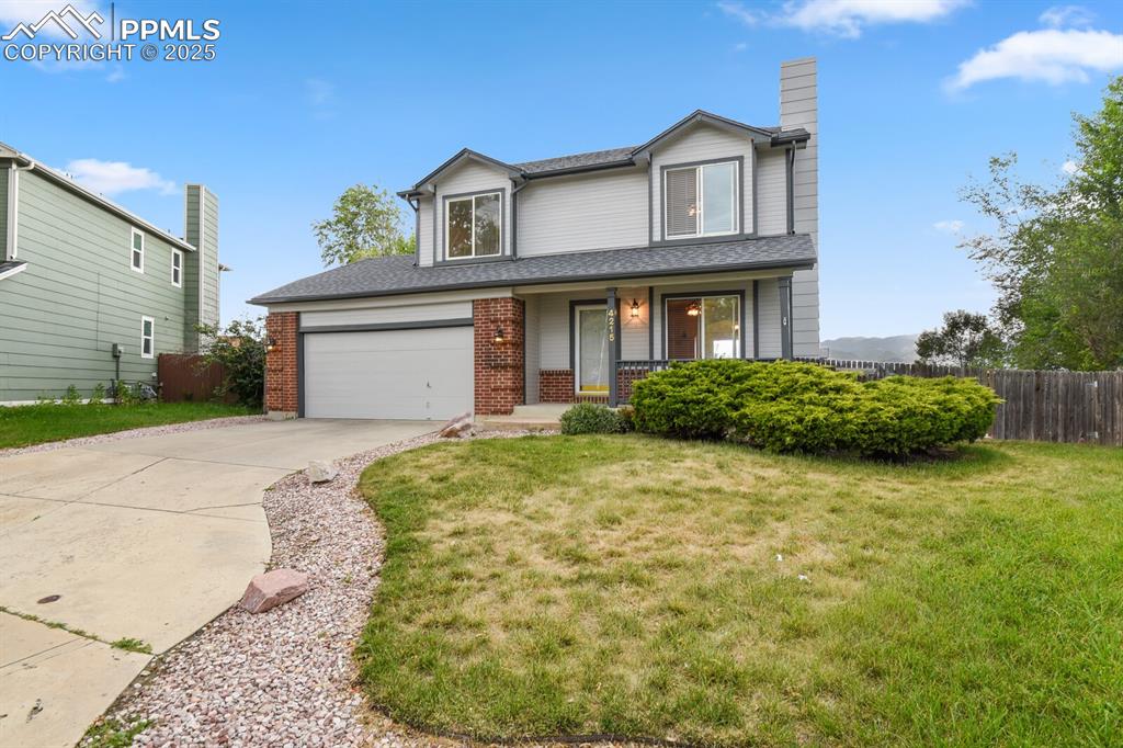 Image 2 of 45: Traditional-style house with concrete driveway, a porch, brick siding, a ch