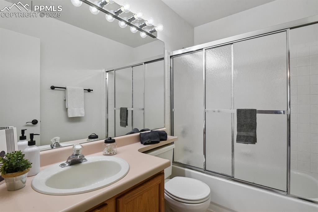 Image 20 of 45: Full bath featuring vanity and shower / bath combination with glass door