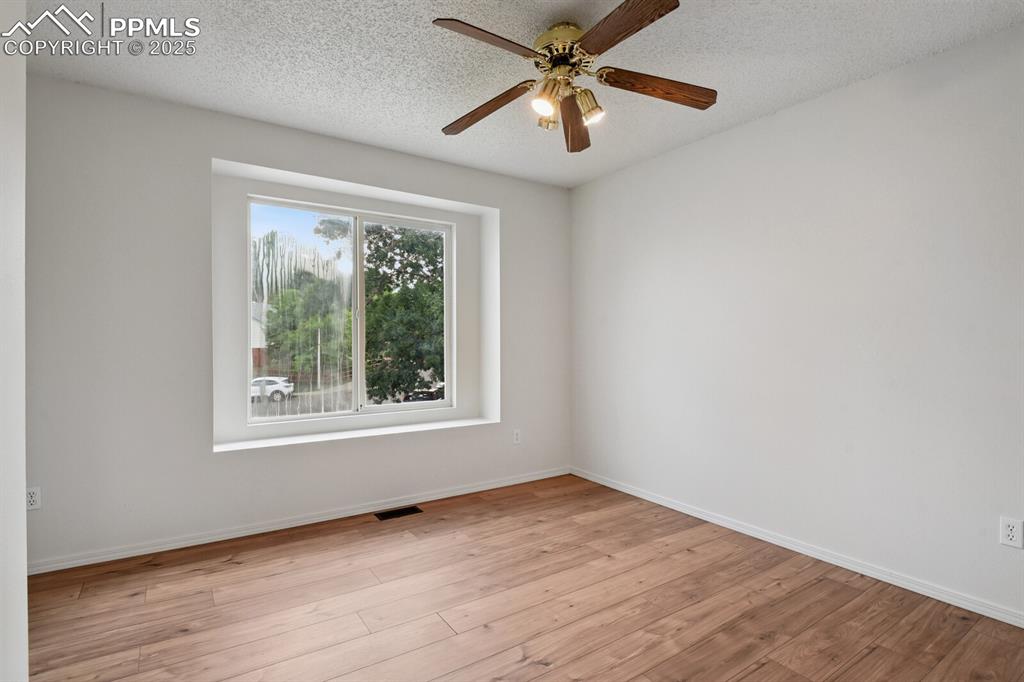 Image 27 of 45: Spare room featuring light wood-type flooring, ceiling fan, and a textured 