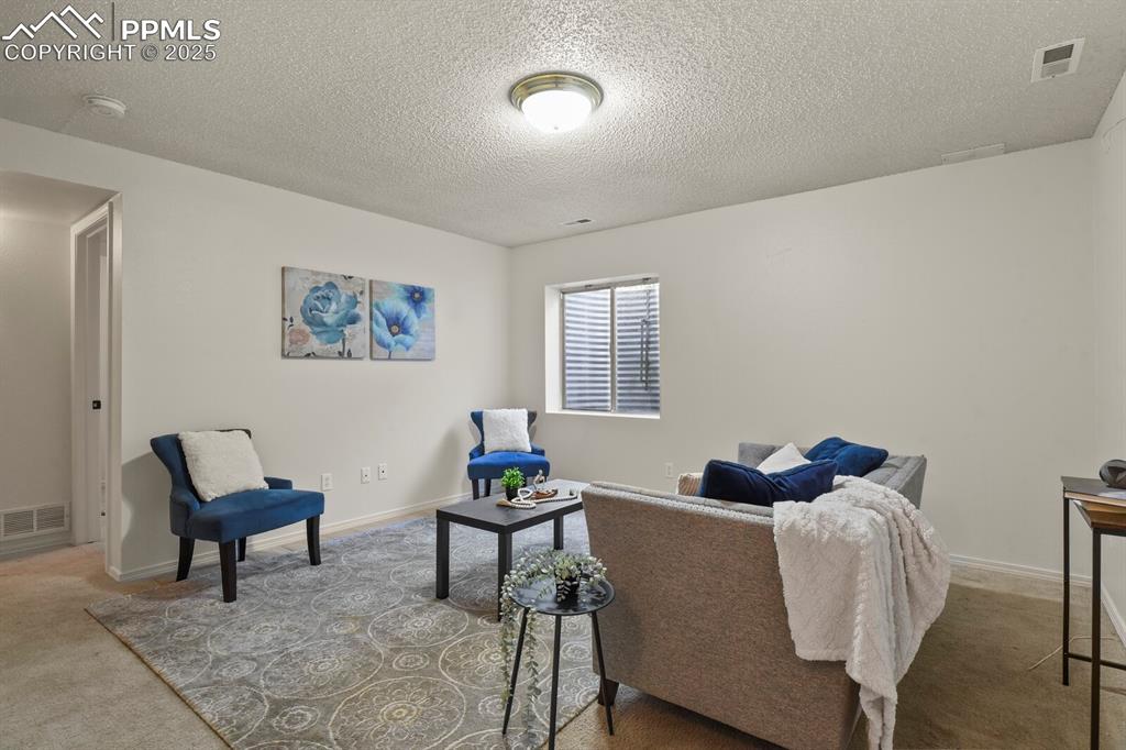 Image 29 of 45: Carpeted living room with a textured ceiling and baseboards