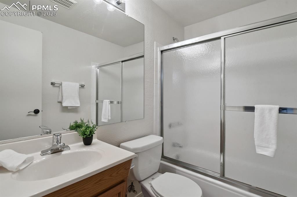 Image 34 of 45: Bathroom featuring vanity and bath / shower combo with glass door