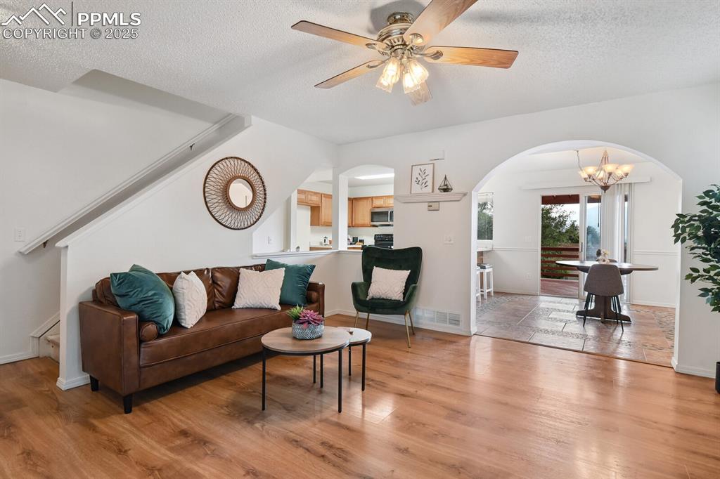 Image 5 of 45: Living area featuring arched walkways, light wood-style floors, a textured 