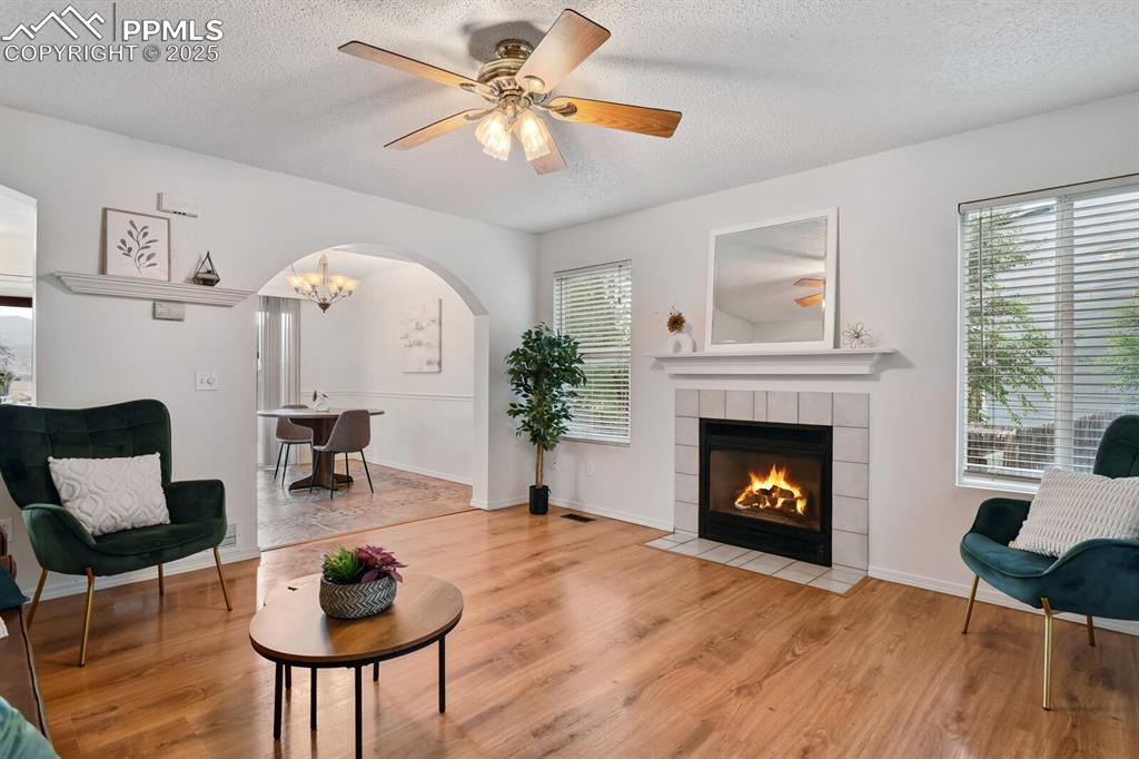 Image 7 of 45: Living area featuring arched walkways, a textured ceiling, light wood finis