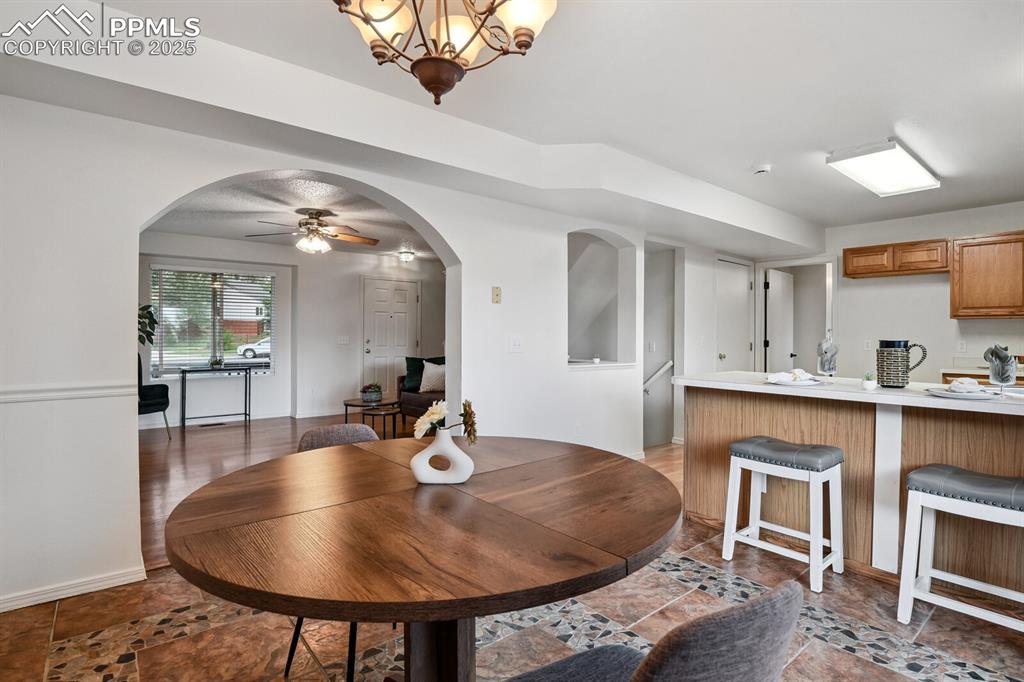 Image 9 of 45: Dining space featuring ceiling fan, arched walkways, and a chandelier
