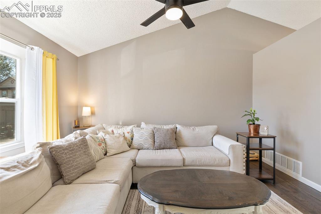 Image 10 of 29: Living area featuring lofted ceiling, wood finished floors, a textured ceil