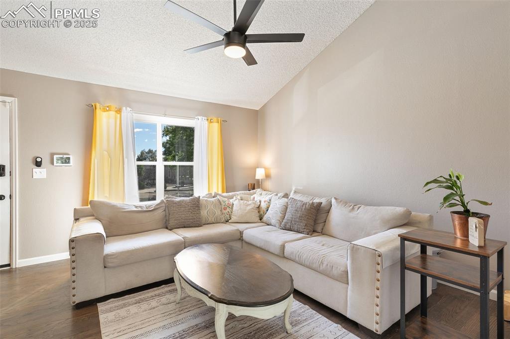 Image 11 of 29: Living area with a textured ceiling, wood finished floors, lofted ceiling, 