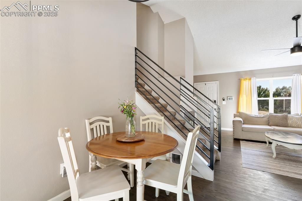 Image 17 of 29: Dining area with stairs, wood finished floors, ceiling fan, and high vaulte