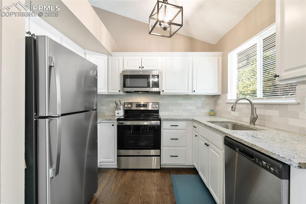 Image 18 of 29: Kitchen with appliances with stainless steel finishes, light stone counters