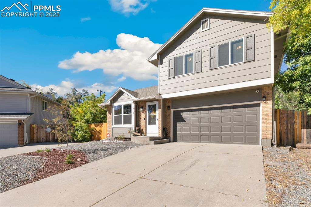 Image 2 of 29: View of front of property with brick siding, a garage, and driveway