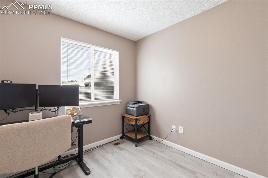 Image 28 of 29: Office with a textured ceiling and light wood-type flooring