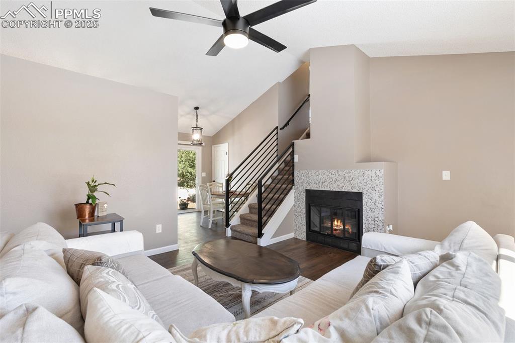 Image 9 of 29: Living area featuring wood finished floors, lofted ceiling, a fireplace, st
