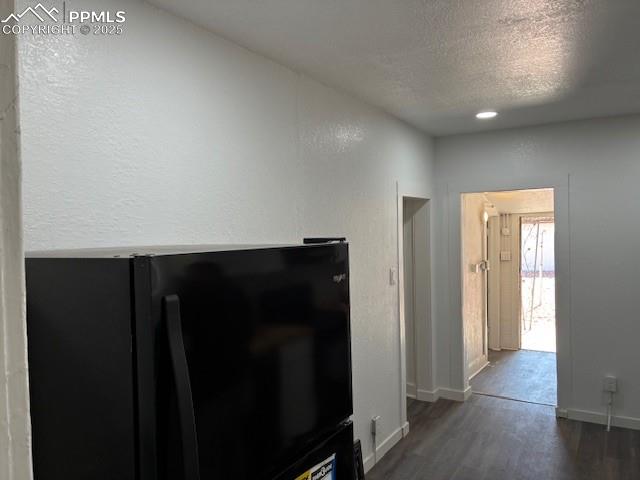 Image 10 of 13: Unfurnished living room featuring a textured ceiling, dark wood-type floori