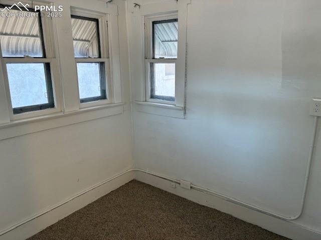 Image 5 of 13: Unfurnished room featuring dark colored carpet and baseboards
