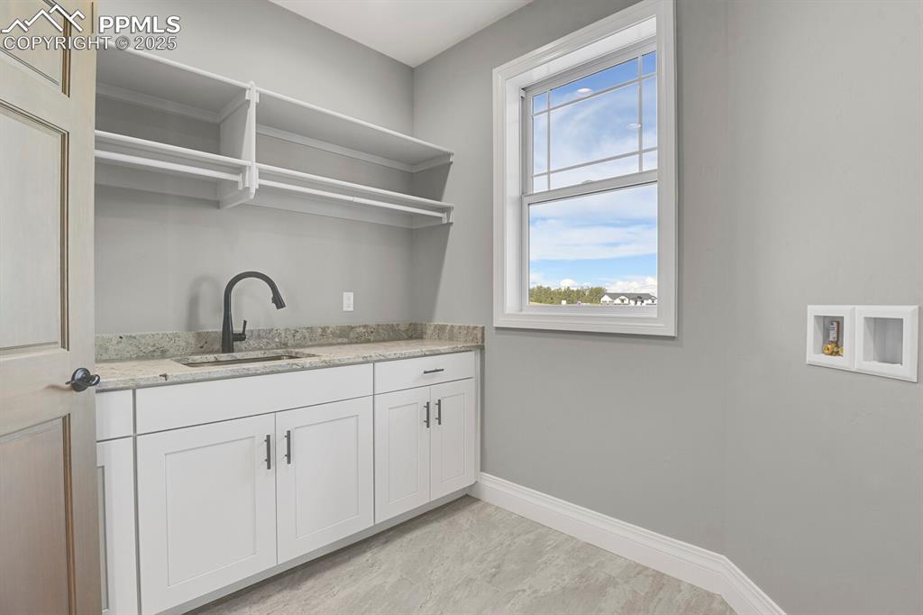 Image 10 of 44: Main level laundtry room w/sink, window and storage