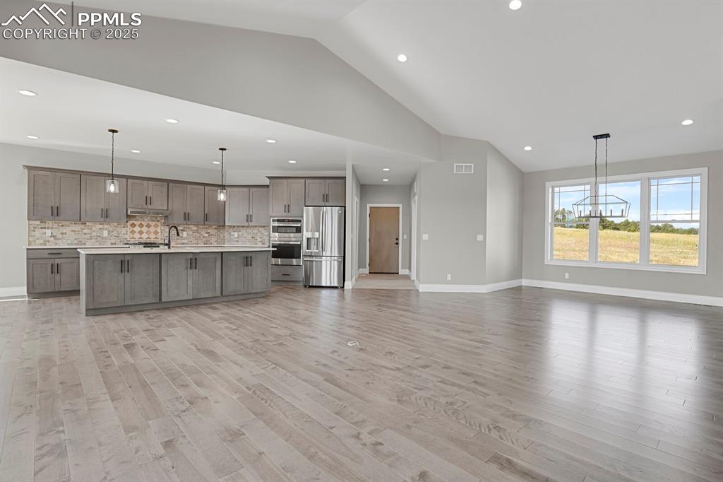 Image 6 of 44: Kitchen and dining area view from fireplace.  Door at the far end is the ga