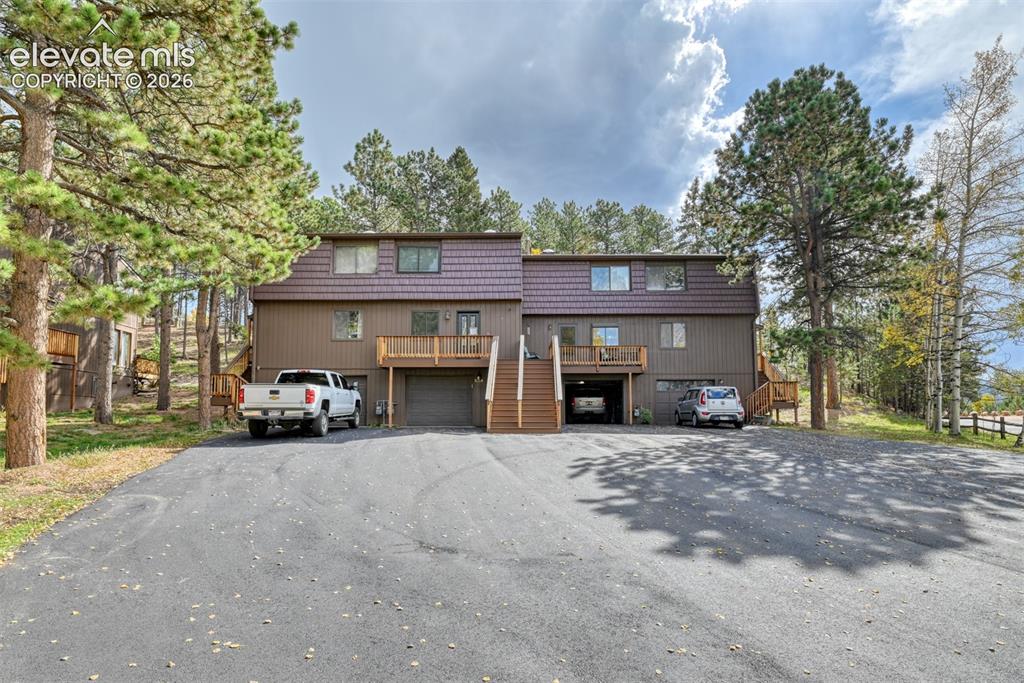 Caption: Two-story multi-unit dwelling with brown siding, textured roof, and integrated garage spaces