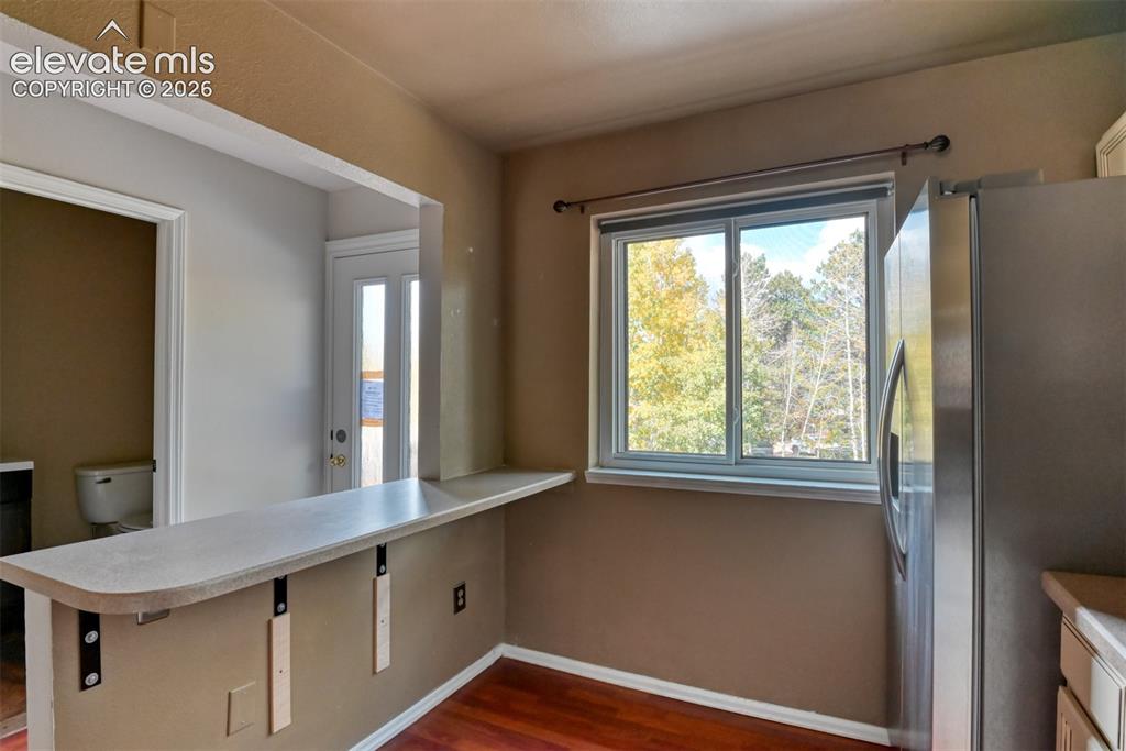 Image 10 of 50: Built-in counter with support brackets, wood-finish flooring, and a large w