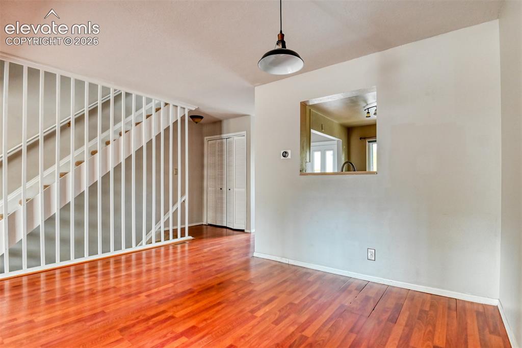 Image 13 of 50: Wood-finish flooring, white spindle stair railing, built-in pass-through wi