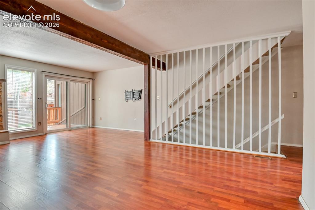 Image 14 of 50: Hardwood-finish flooring, exposed wooden beam, and sliding glass door