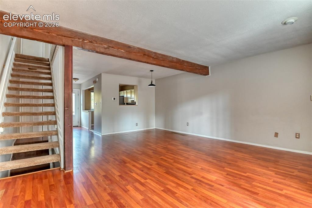 Image 17 of 50: Hardwood-style flooring throughout, exposed wood beam, stairway with carpet