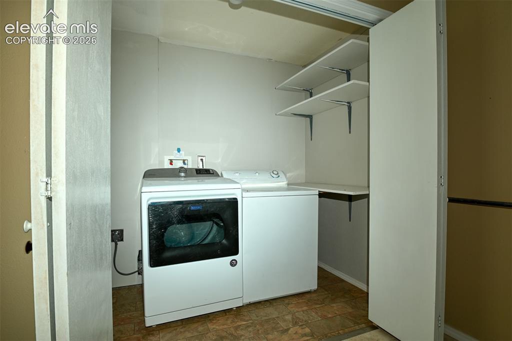 Image 21 of 50: Dedicated laundry area with durable flooring, built-in shelving, and a fold