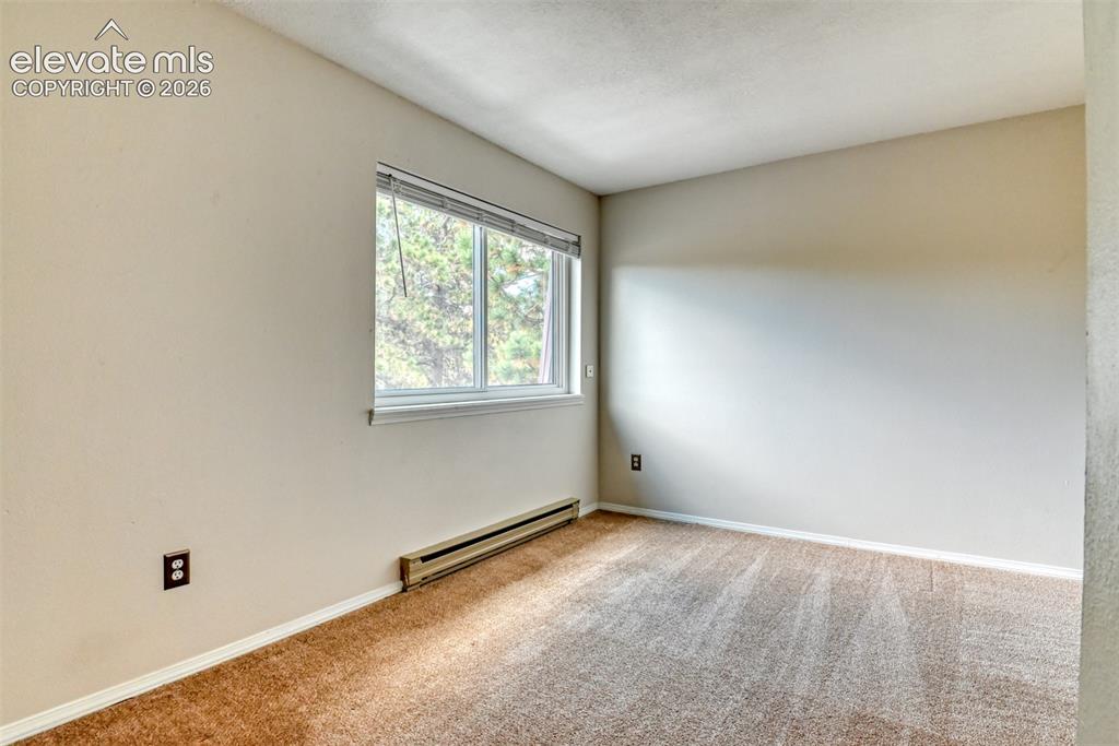Image 22 of 50: Neutral-toned carpeting, white window trim, and baseboard heating unit