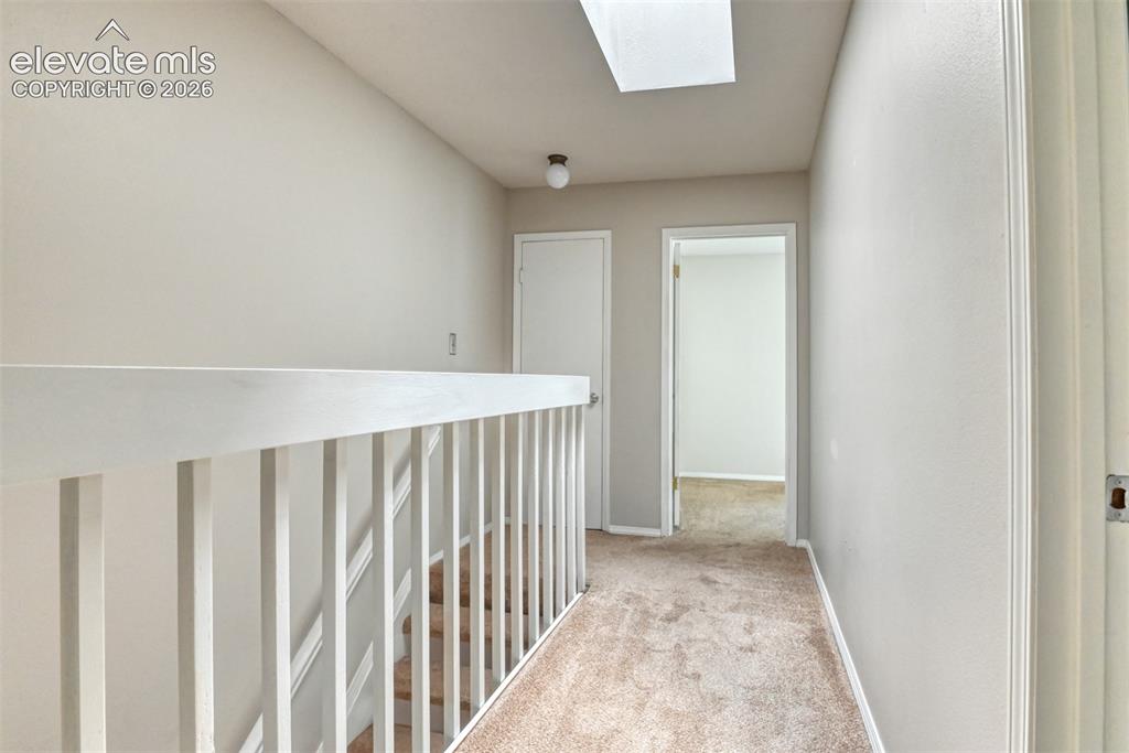 Image 28 of 50: Skylight, neutral carpeting, white balustrade, and light wall finishes