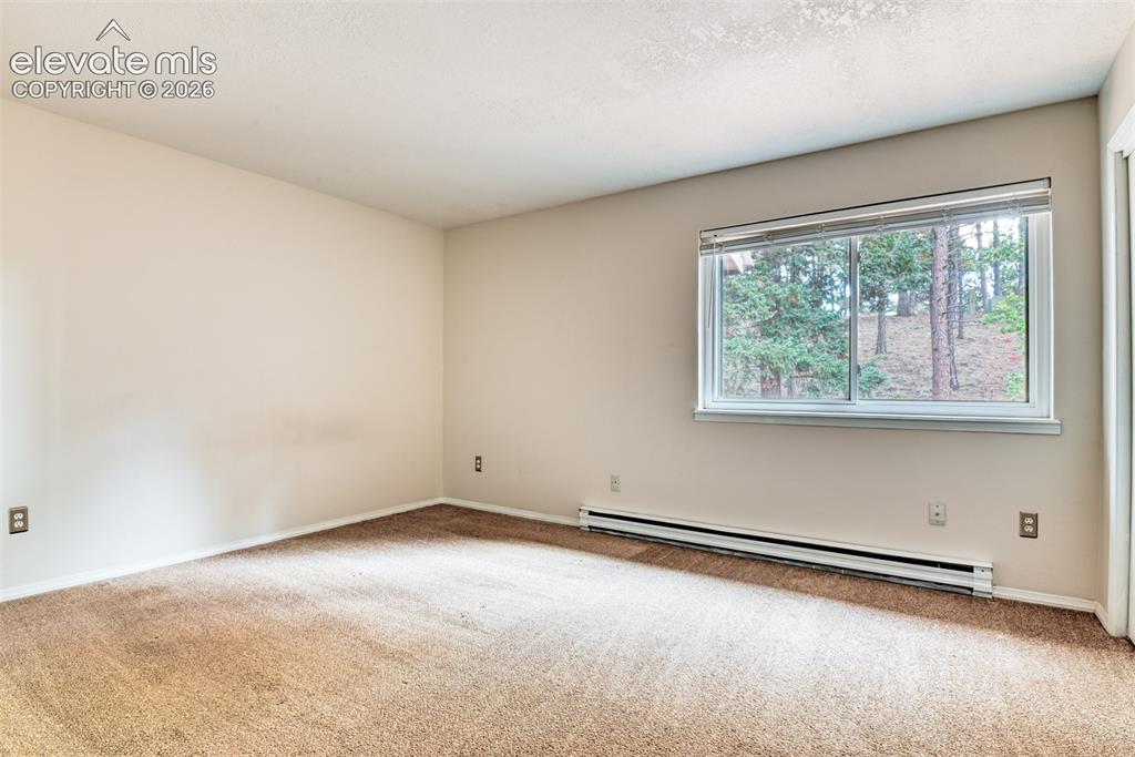 Image 29 of 50: Window with white blinds, wall-mounted baseboard heating unit, and neutral-