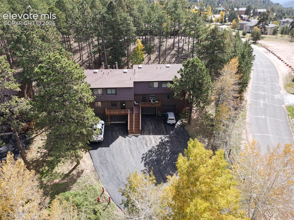 Image 34 of 50: Duplex structure with brown siding and a dark shingle roof, surrounded by m