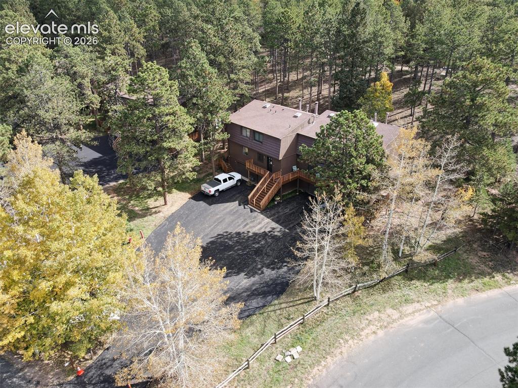 Image 35 of 50: Wood-sided exterior with multiple levels, expansive paved driveway, and nat